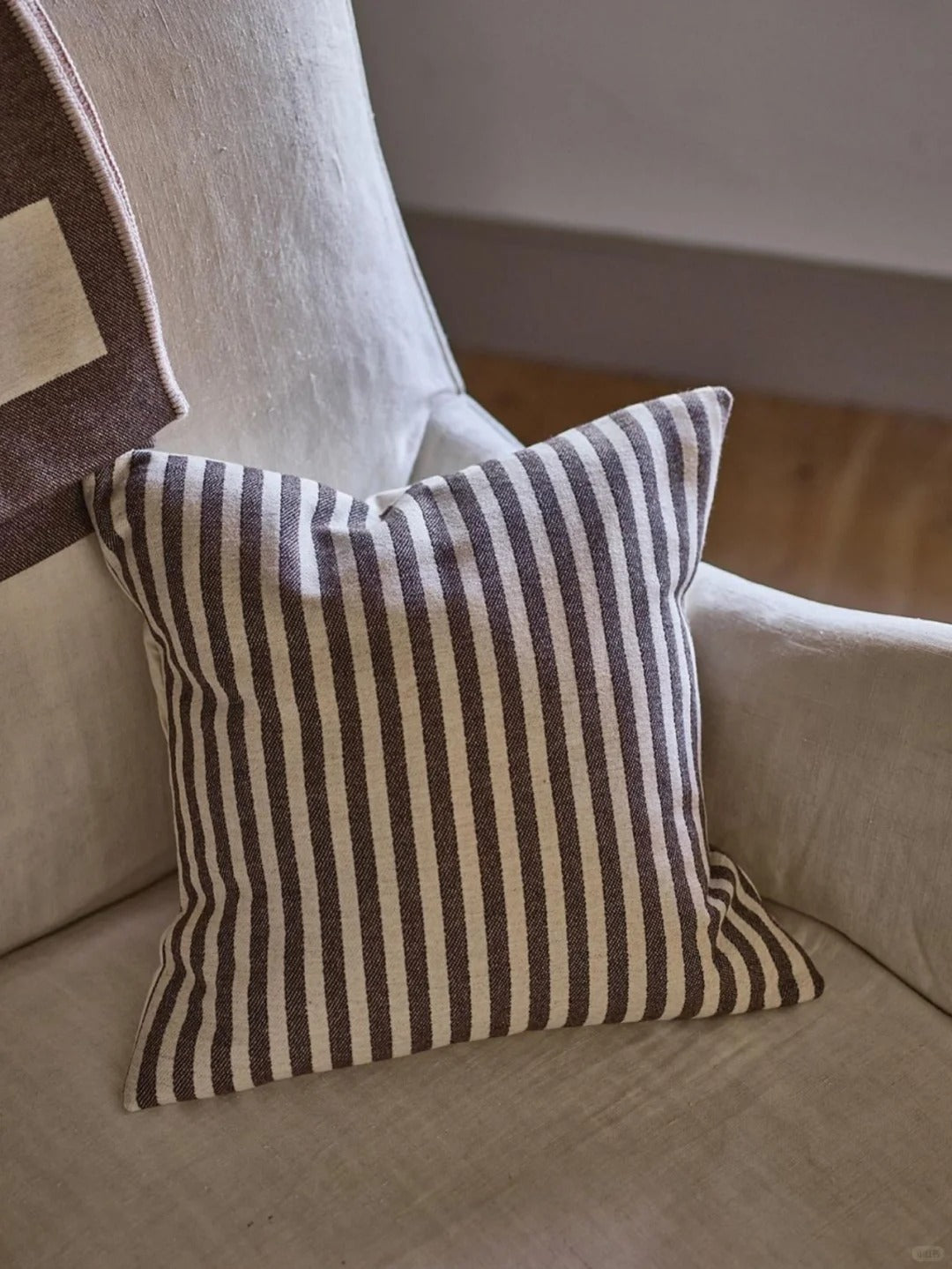 striped linen cushion on beige chair in cozy modern home interior