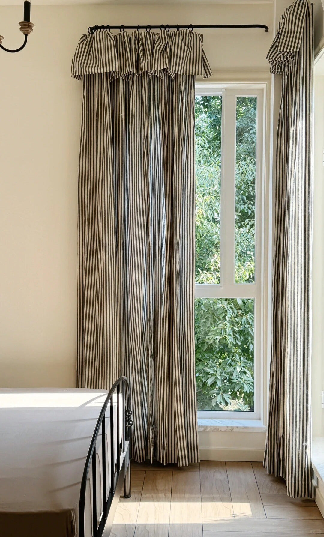 Classic linen striped curtains in neutral tones with fine and bold stripe widths hanging in a modern bedroom with natural light.