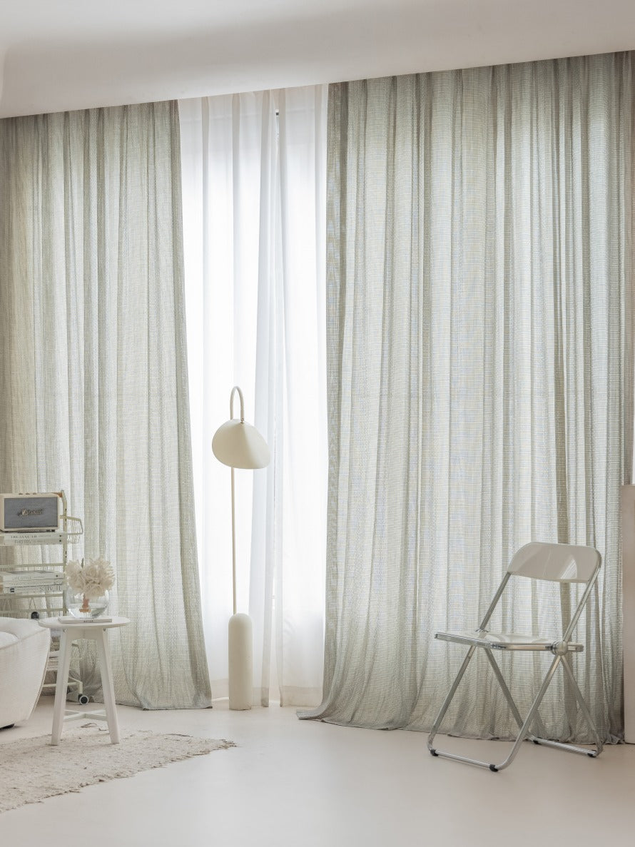 Smoky green net curtains in a modern living room setting, showcasing sheer German-imported fabric.