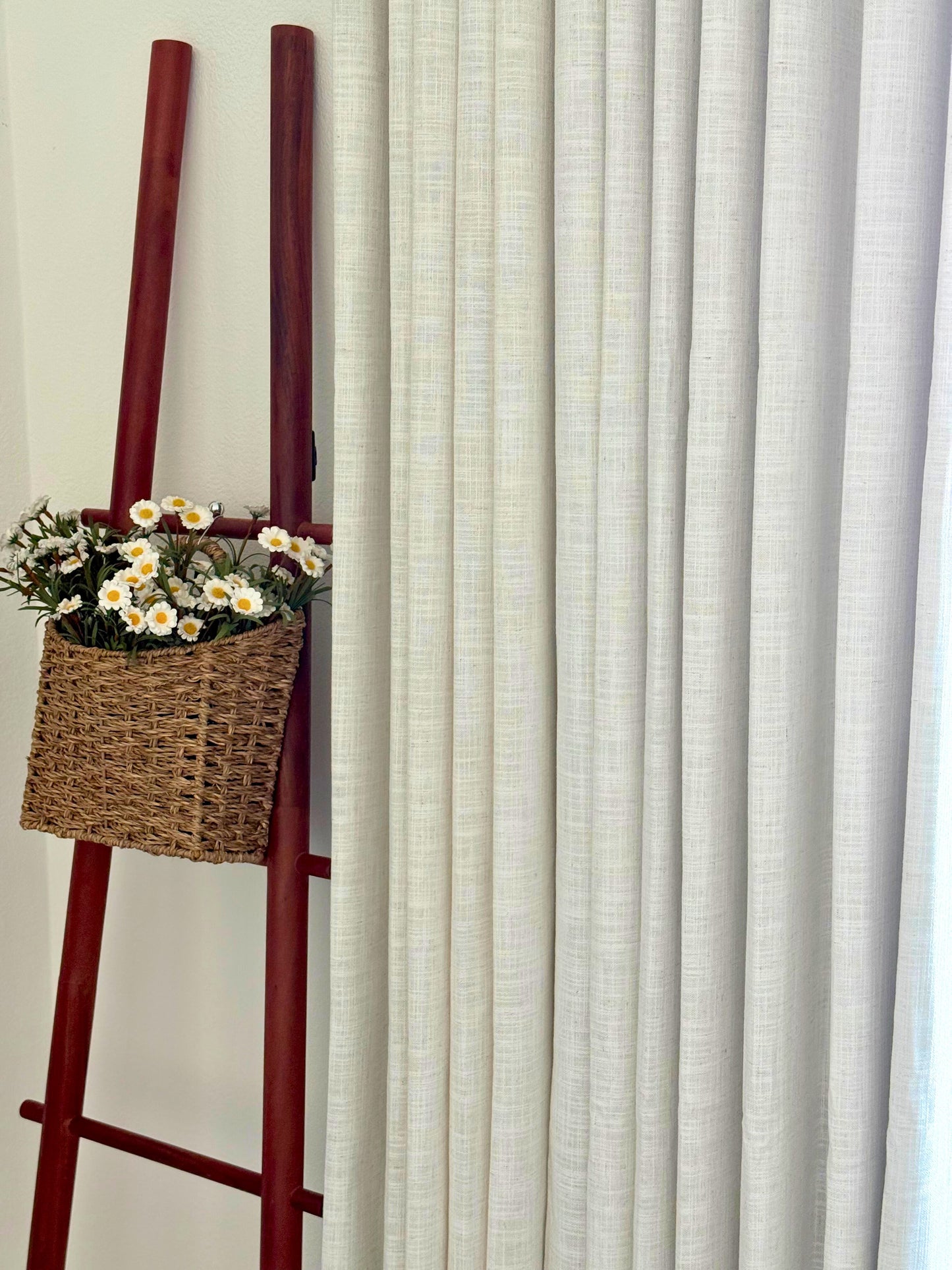 Hunter Douglas Style linen blackout curtains in light neutral color with woven texture hanging beside decorative ladder with wicker basket of flowers