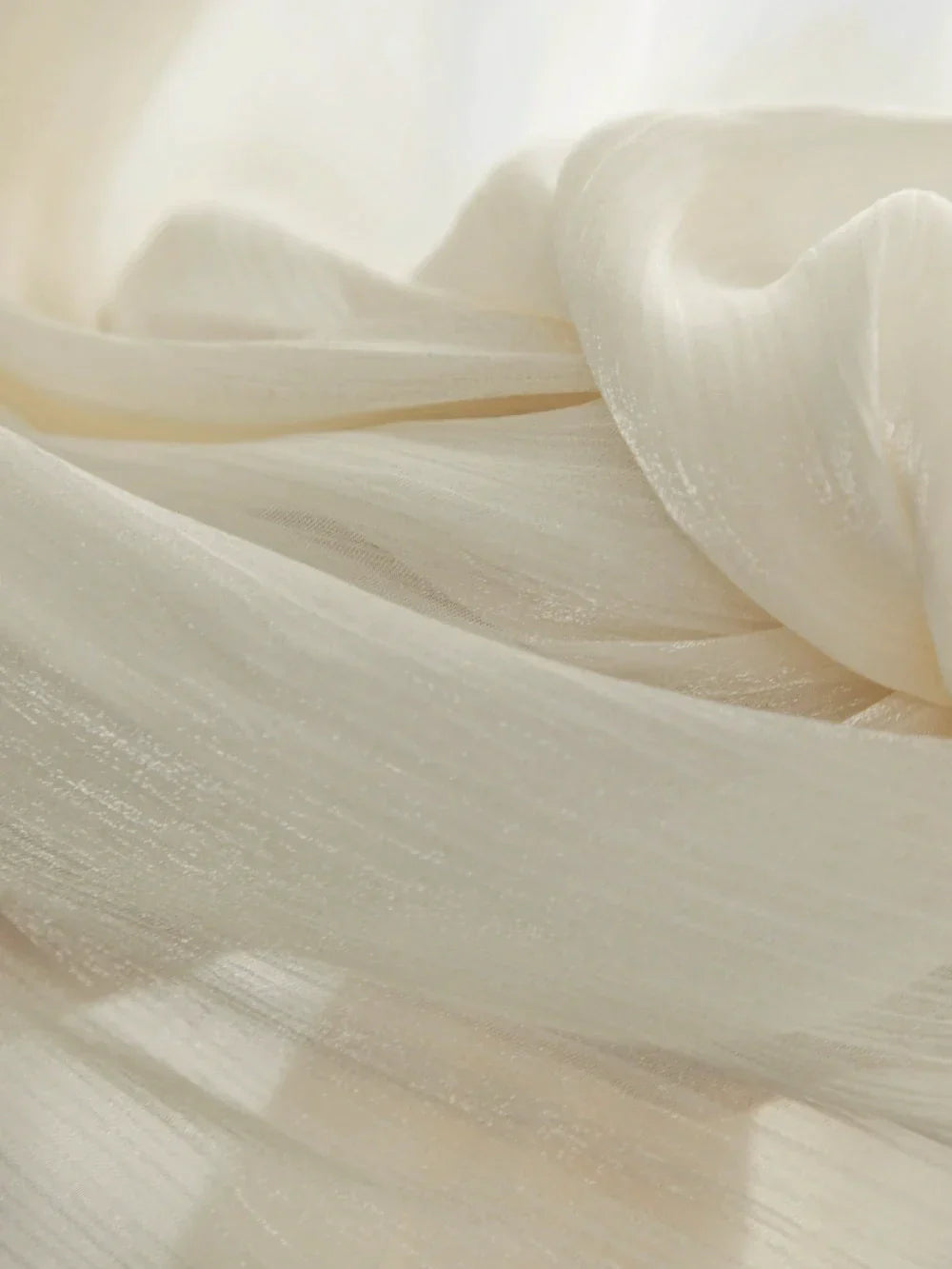 Cream-colored sheer curtains with radiant shimmering finish and soft translucent texture for sunrooms