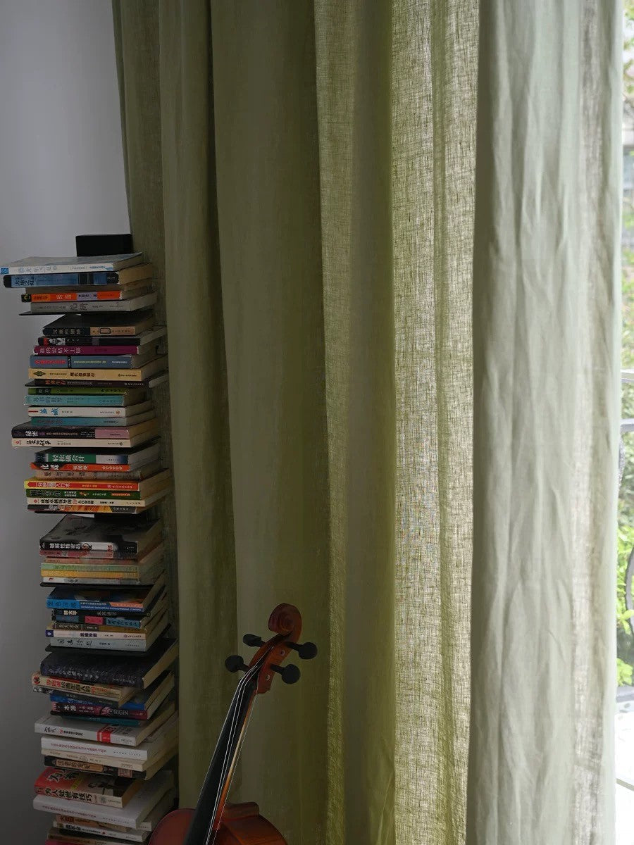sage green linen curtains with natural texture in living room near stacked books and violin