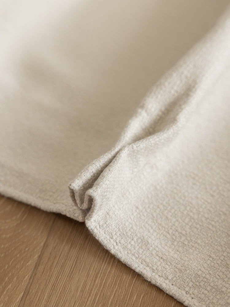 Heavyweight linen blend white blackout curtains on wooden floor.