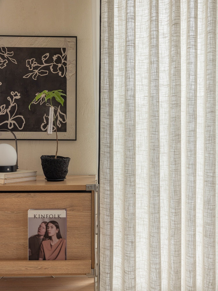 Sheer linen curtains with black trim in a living room setting.