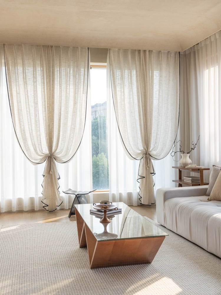 Sheer linen curtains with black trim in a modern living room.
