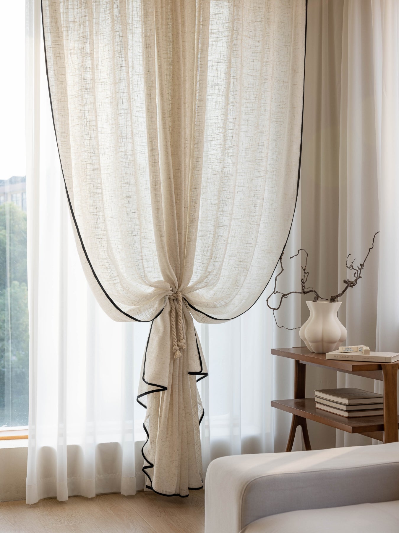 Black-trimmed sheer linen curtains in living room setting, elegant and modern design.