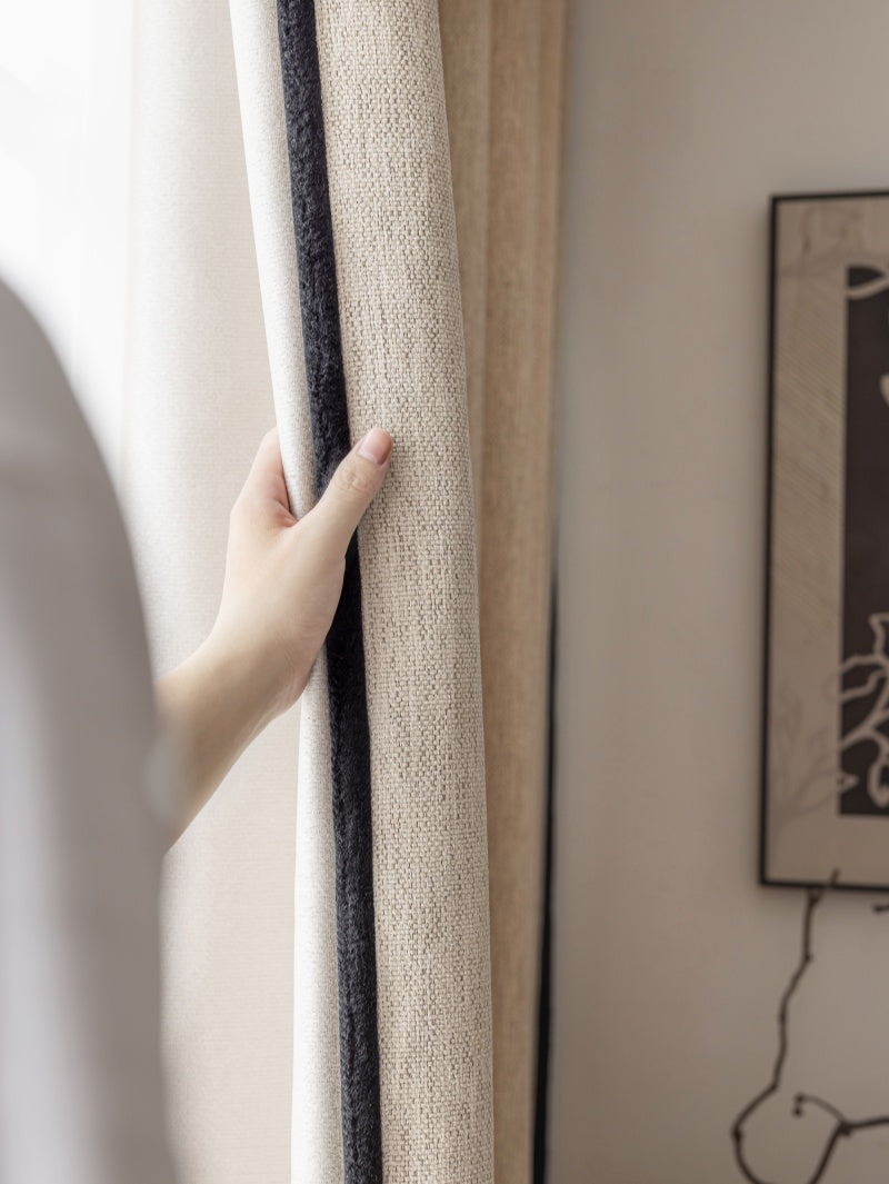 Hand holding heavyweight chenille blackout custom curtains in a neutral color, showcasing rich texture and premium quality.