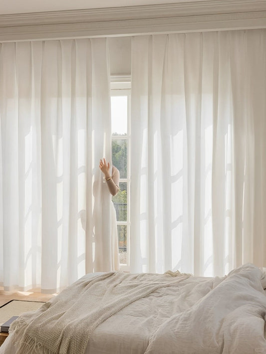 White sheer curtain enhancing privacy and light penetration in a bright bedroom.