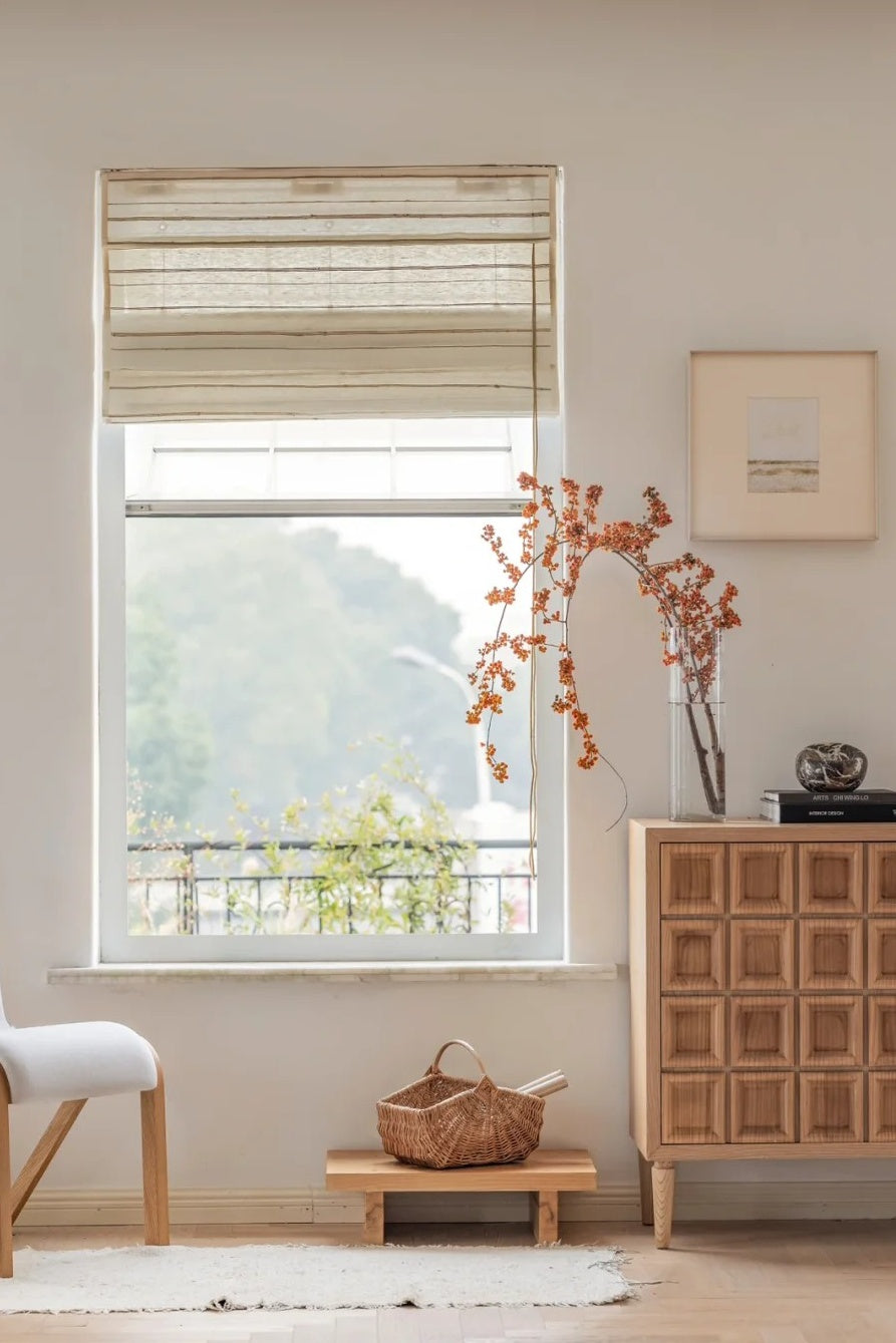 Ivory sand natural ramie bamboo blinds hanging in a bright living room with wooden furniture and decorative vase