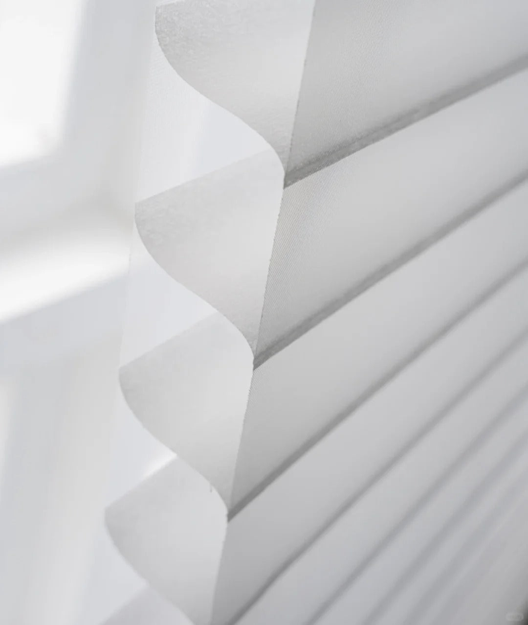 Light-filtering sheer shades on a window, showcasing translucent fabric and adjustable blades for privacy and light control.