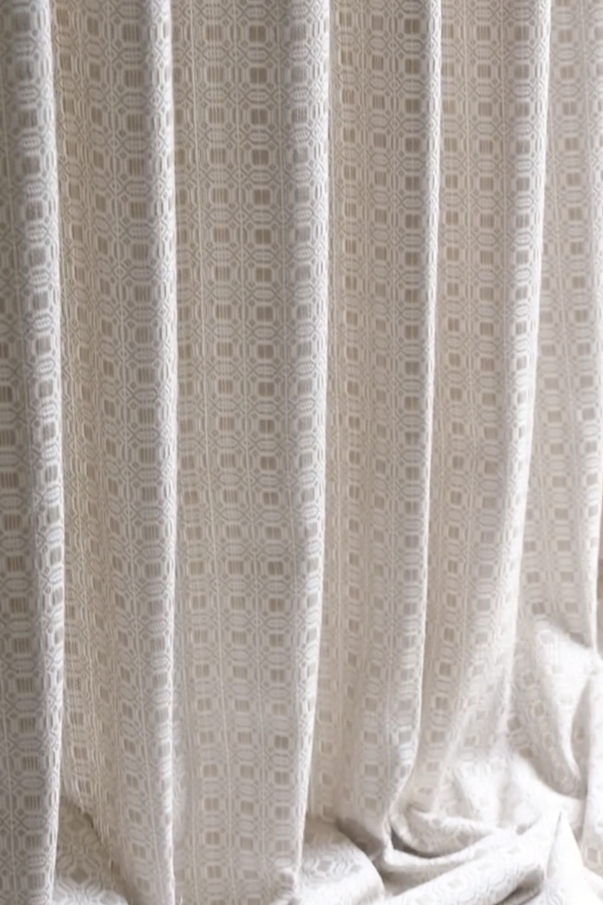 Cream-colored vintage curtains with textured geometric patterns, elegant and classic design.