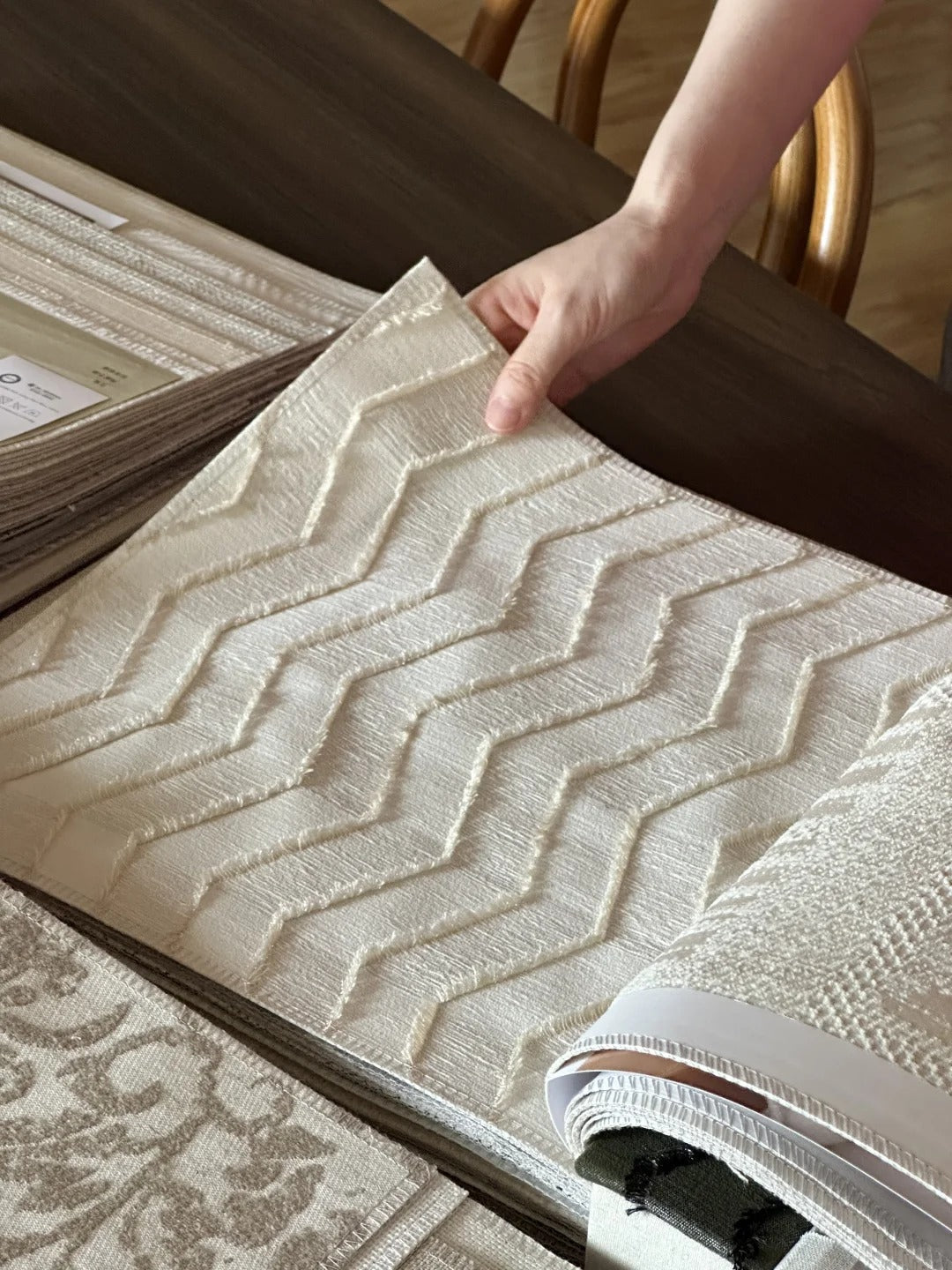 Person selecting free fabric swatches with textured patterns for home decor evaluation.
