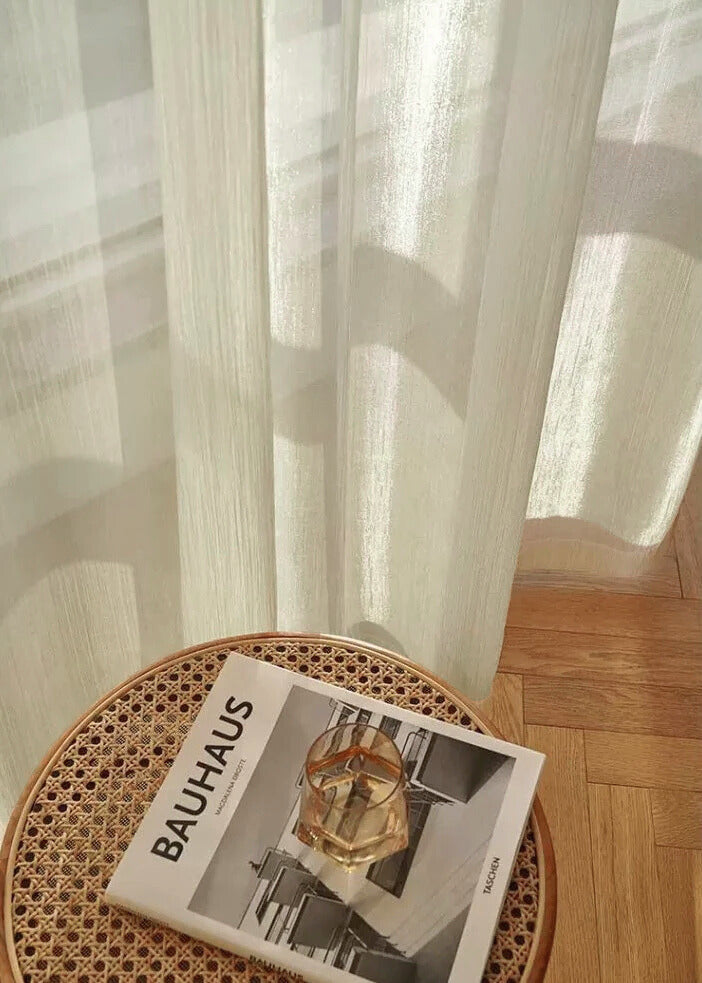 Cream sheer curtains with radiant shimmer filtering sunlight in a sunroom setting