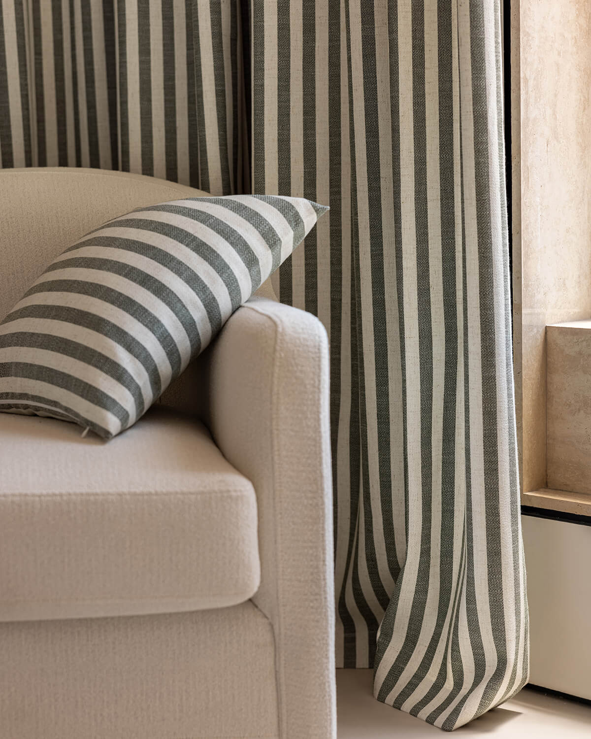 Striped linen curtains and matching striped cushion on beige sofa in modern living room