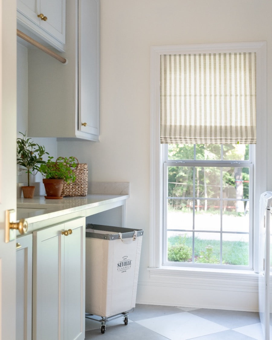 Light filtering striped roman shade in a bright kitchen window with cordless design and classic beige and white stripes