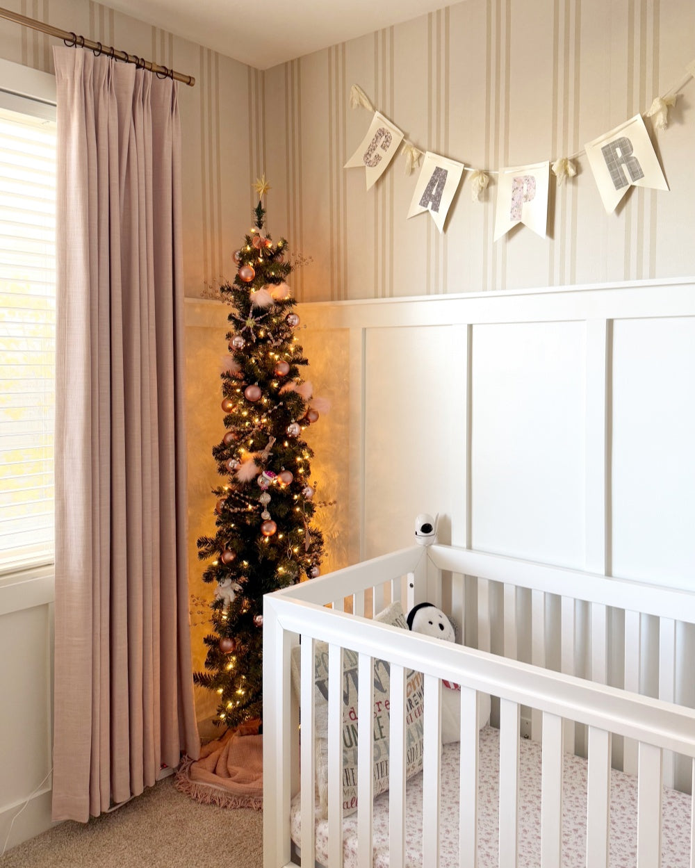 Soft blush linen blackout curtains in nursery room with decorated Christmas tree and white crib