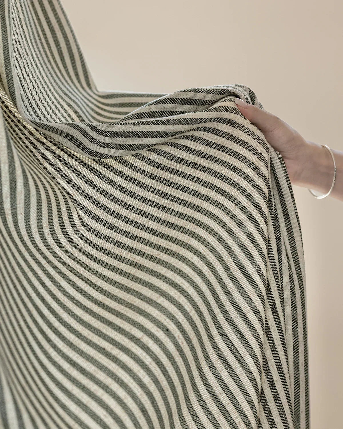 Hand holding classic linen striped curtains with fine black and white stripes and natural texture