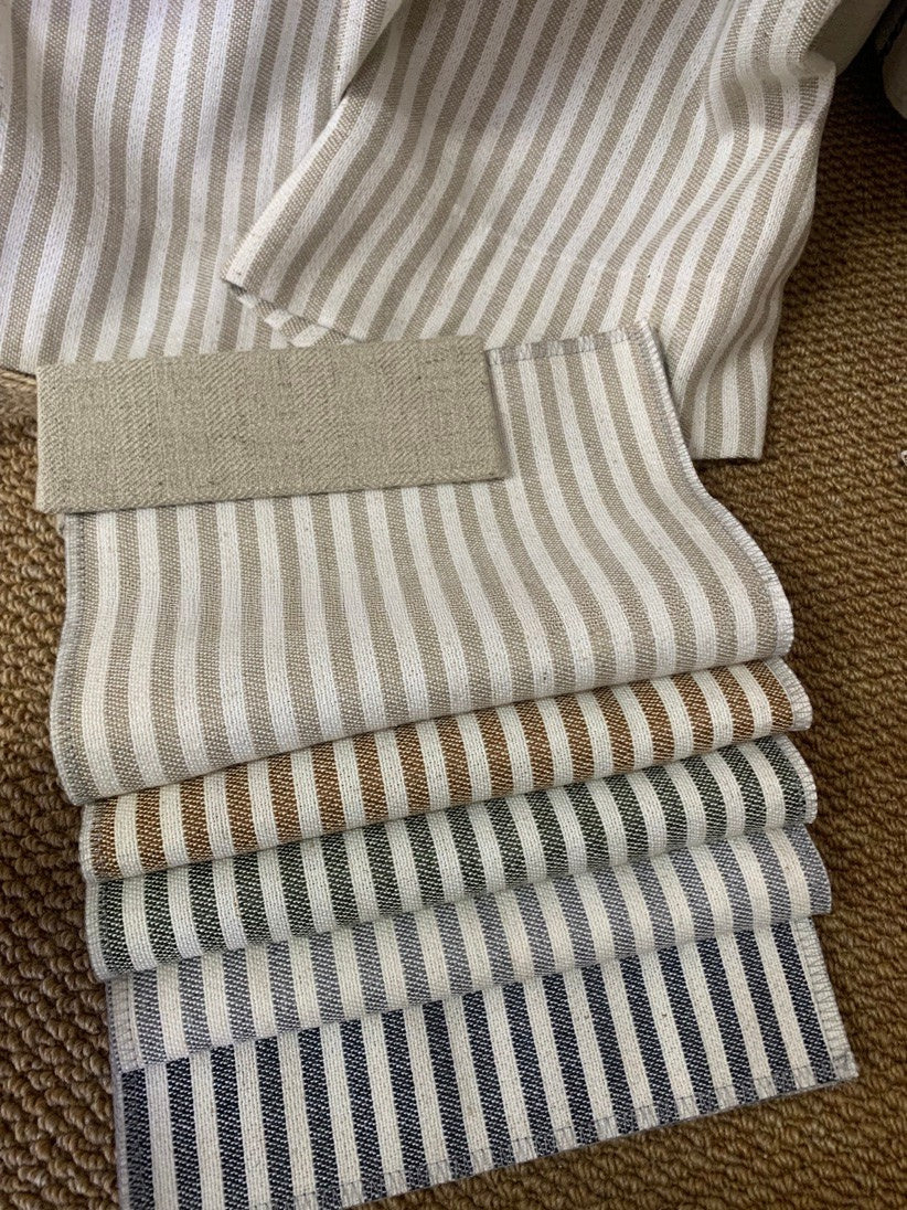 Stack of classic linen striped curtains in neutral tones showing fine and bold stripe patterns on textured fabric