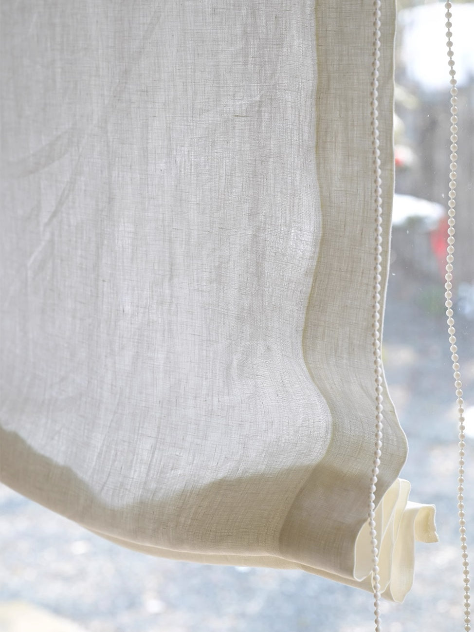 Close-up of soft fold sheer Roman shade made of 100% pure linen gauze gently filtering light with elegant cascading curves