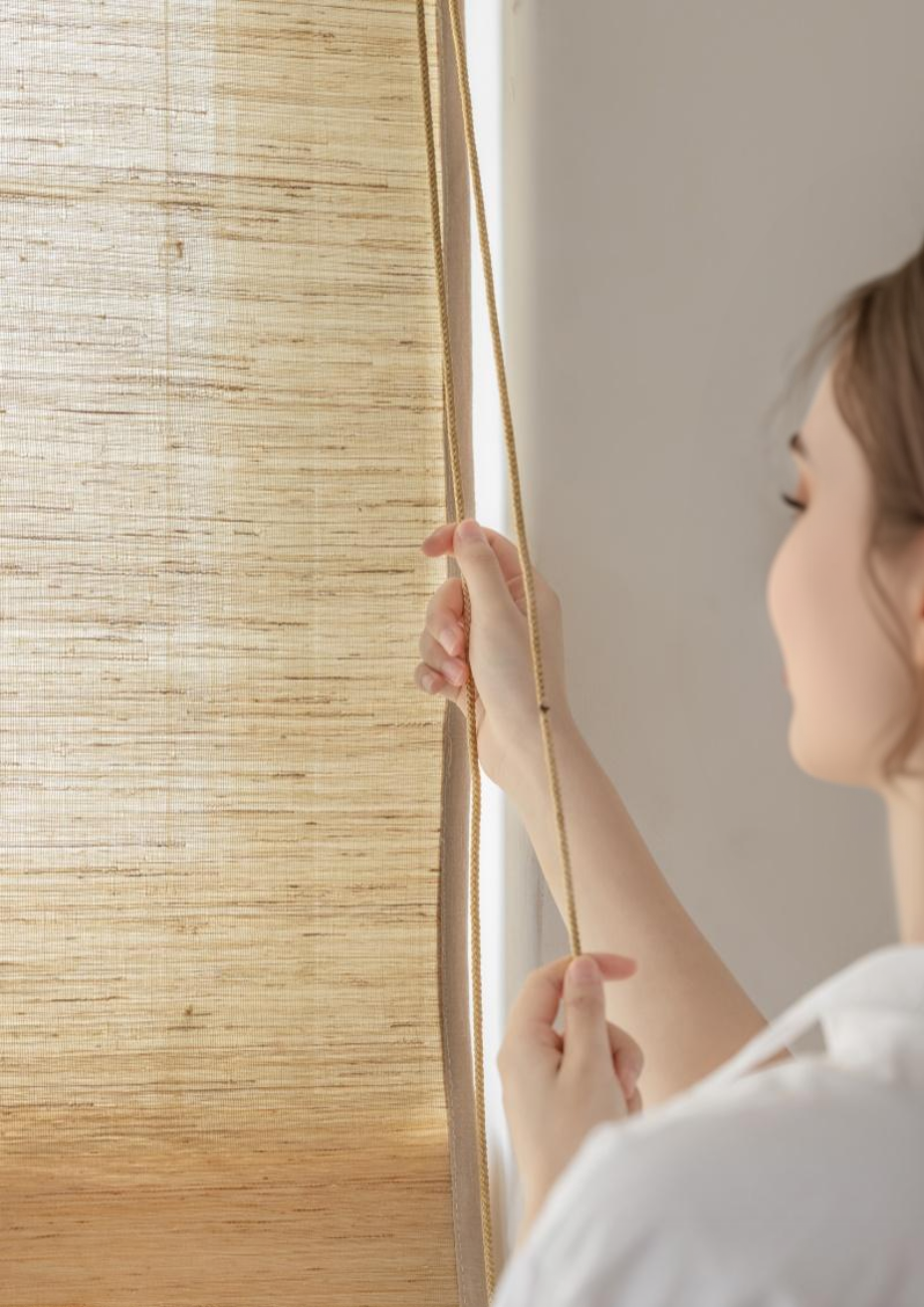 Natural ramie bamboo shades in cashew, mildew-resistant woven blinds being adjusted.