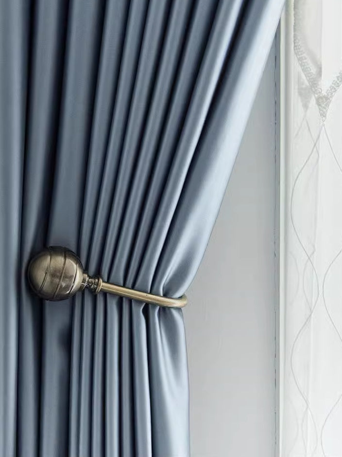Elegant blue silk curtain with tieback, showcasing smooth draping and luxurious sheen.