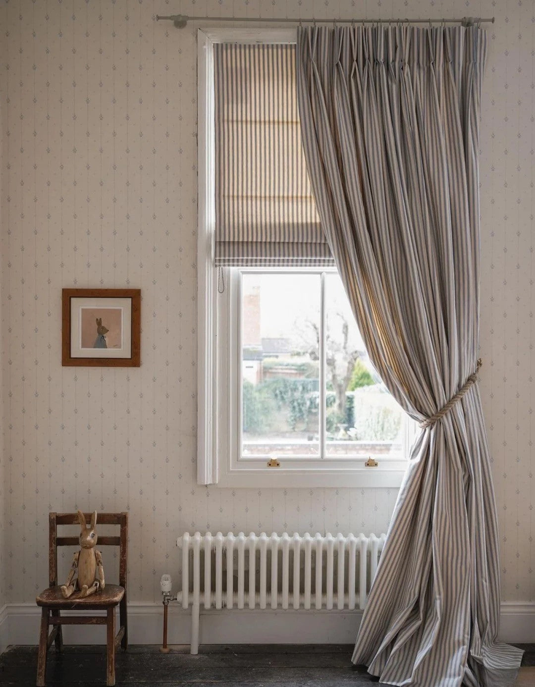 Classic linen striped curtains in neutral tones with fine vertical stripes hanging beside a window in a cozy room.