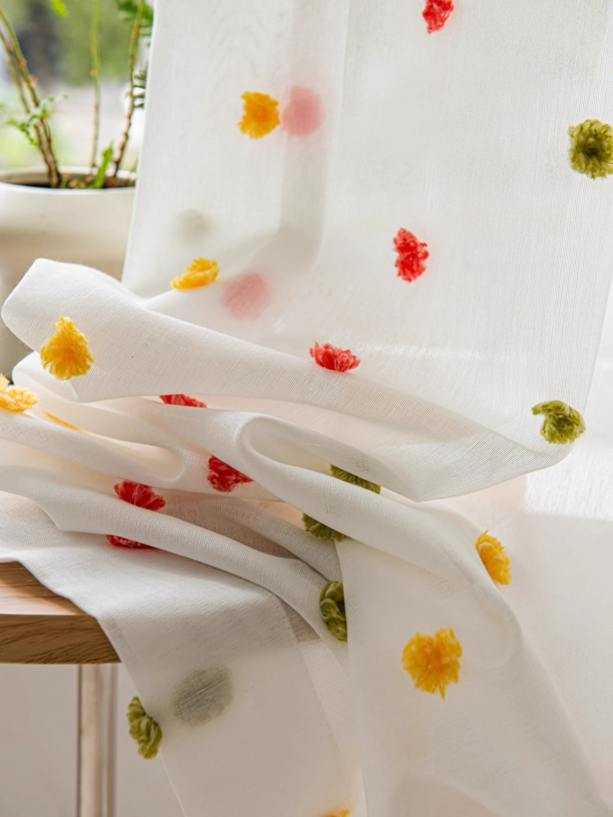 Colorful candy-themed kids sheer curtains with whimsical pom-poms in blue-green and red-yellow, adding playful charm to any room.