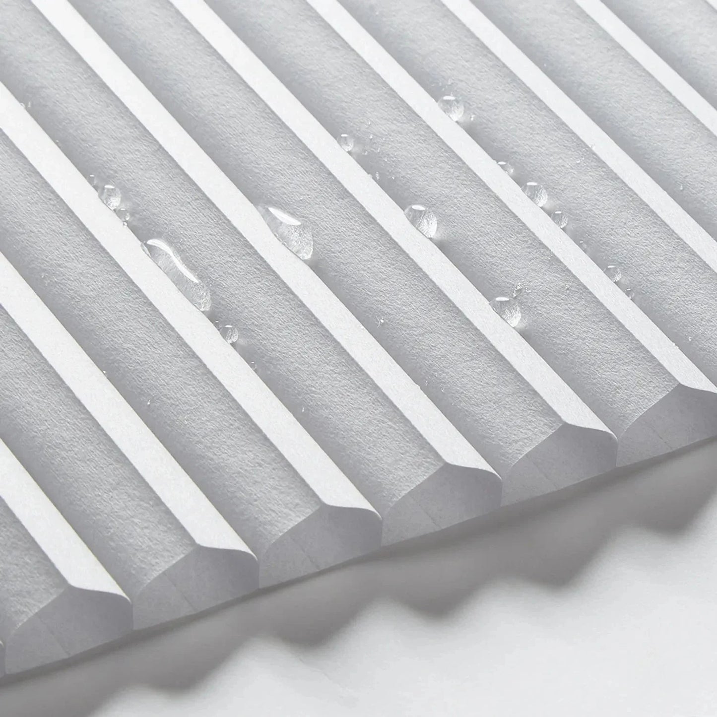 Close-up of waterproof bathroom blinds with a cordless honeycomb design, featuring water droplets on the surface.