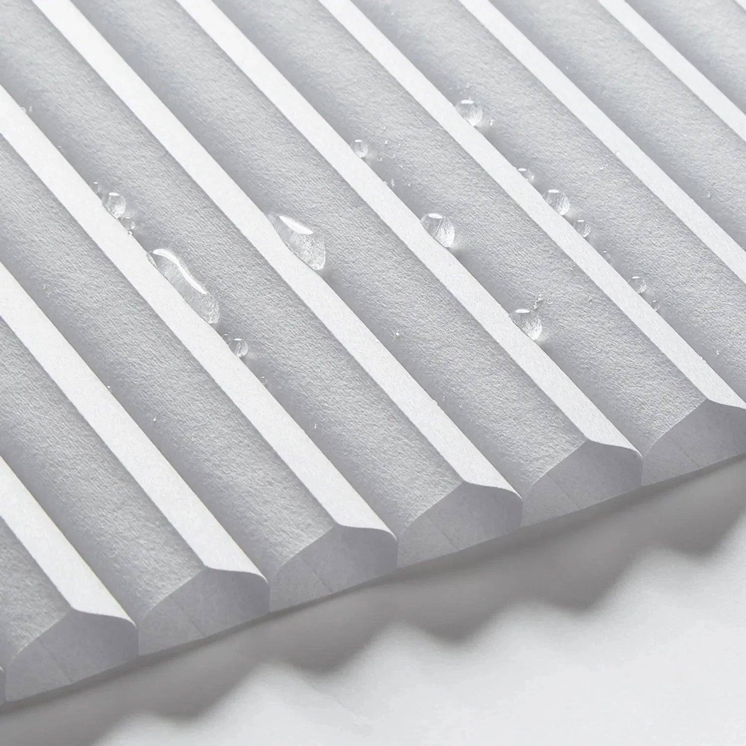 Close-up of waterproof bathroom blinds with a cordless honeycomb design, featuring water droplets on the surface.