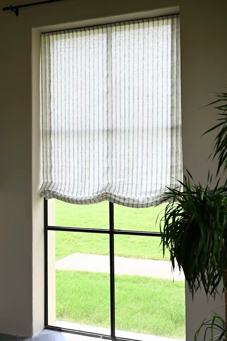 Gray striped roman shades in sheer white fabric with narrow gray vertical stripes and softly scalloped Roman folds