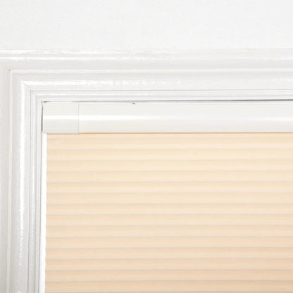 Beige no-drill honeycomb shades installed on a white window frame with tool-free, no-nail system design