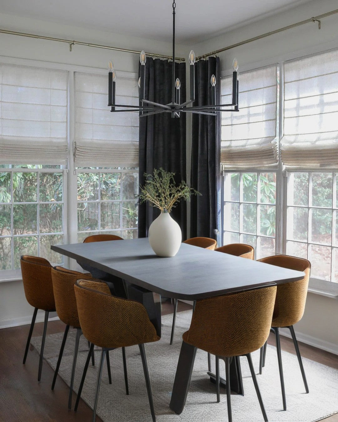 Dining room with cordless custom roman shades and modern chandelier over table with six brown chairs