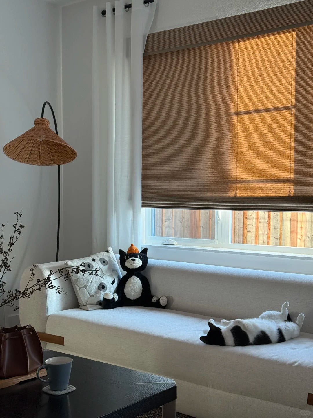 Handcrafted bamboo roman shades filtering warm natural light in cozy living room with beige sofa and decorative pillows