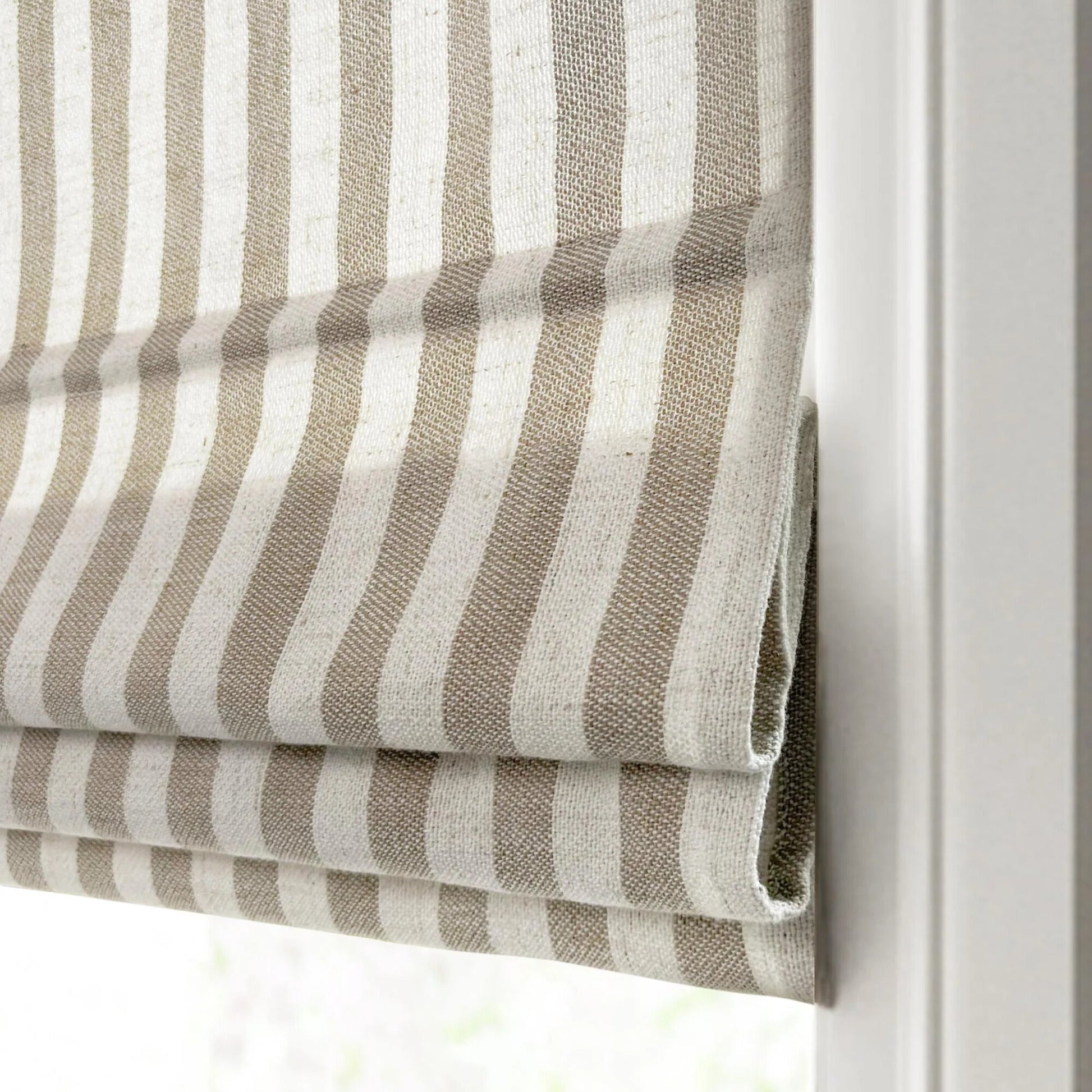 Close-up of beige and white striped custom Roman shades with textured fabric and cordless design