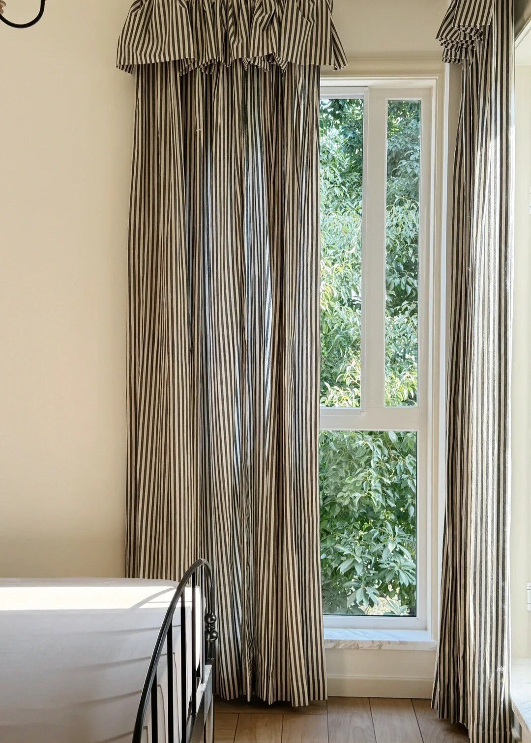 Classic linen striped curtains in neutral tones with fine and bold stripe widths hanging in a modern bedroom with natural light.