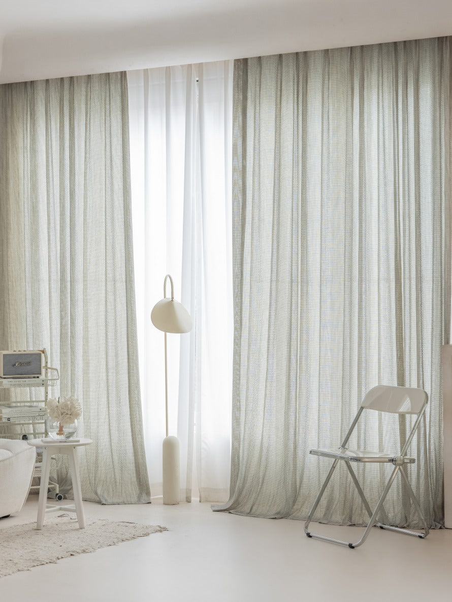 Sophisticated smoky green sheer curtains in a stylish room with delicate mesh weaving, enhancing a minimalist decor.