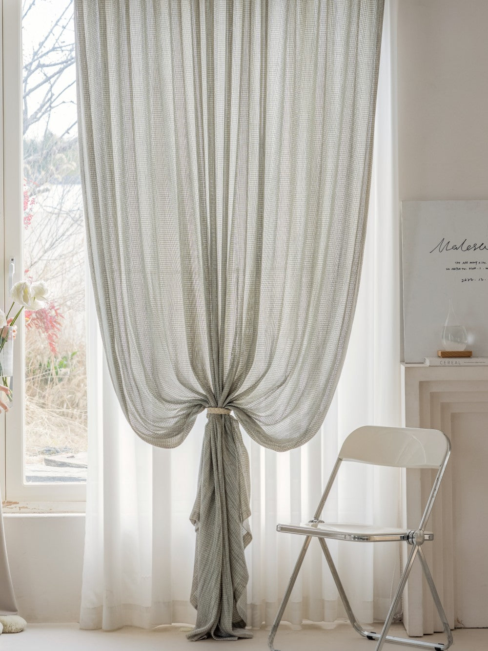 Elegant smoky green sheer curtain imported from Germany, displayed in a sunlit room with minimalist decor, enhancing a serene and sophisticated ambiance perfect for living rooms or studies.