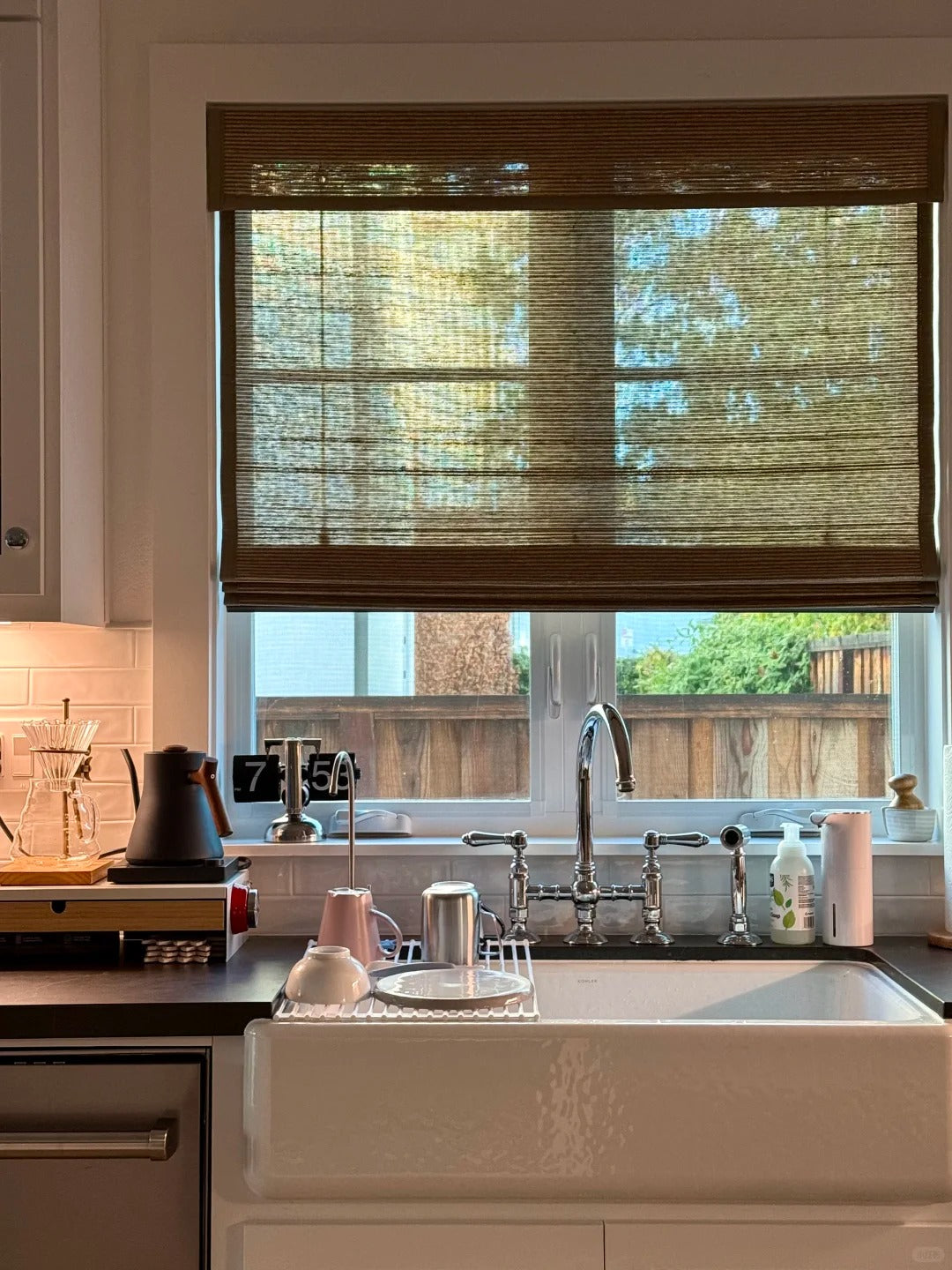 Bamboo roman shades filtering natural light in kitchen window above sink