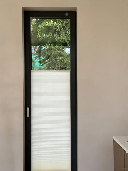 Glass door with honeycomb shade blinds for privacy and style.