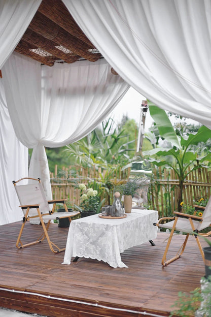 Outdoor curtains on a patio with chairs and a table, providing a light and airy retreat.