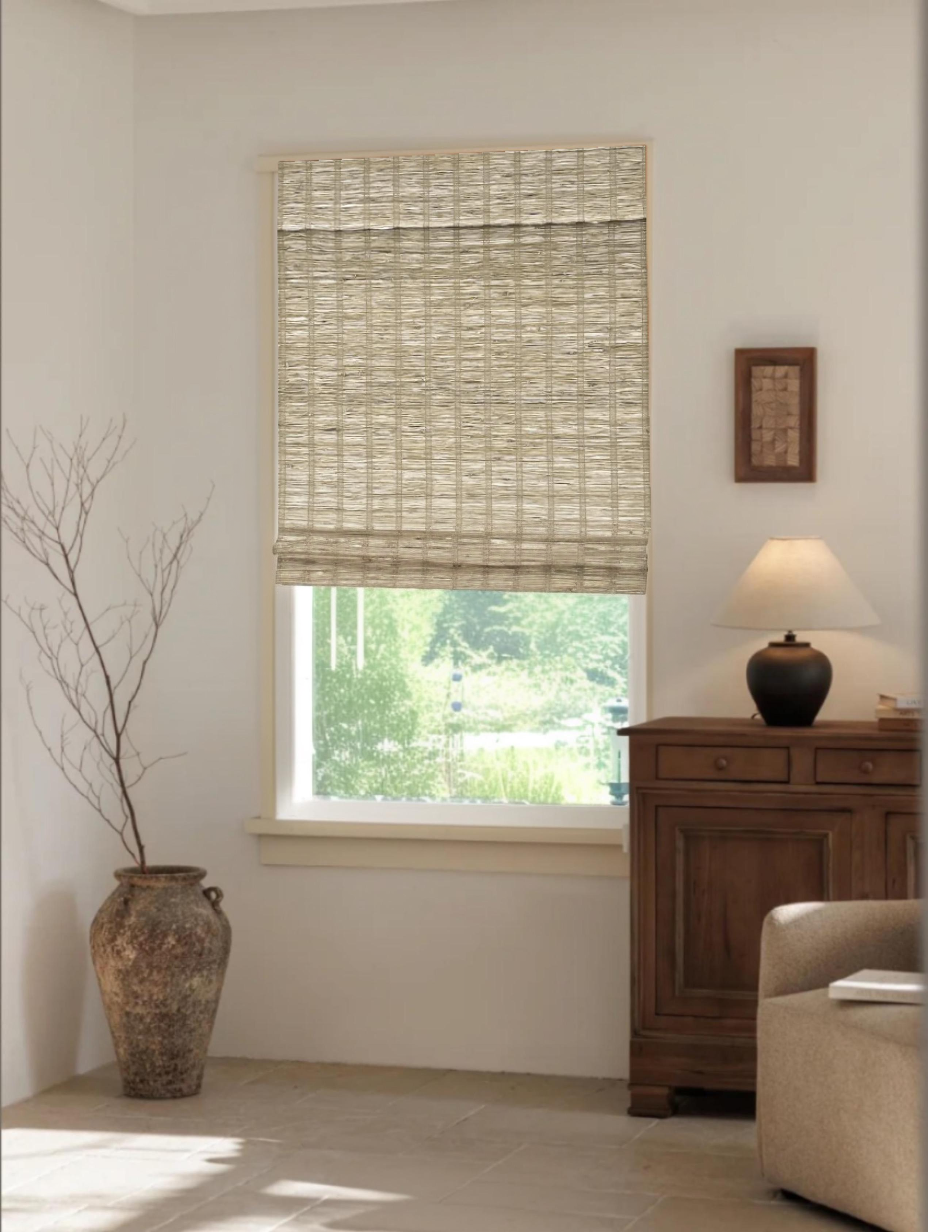 Natural jute bamboo shades outdoor in cinnamon color with woven texture and Roman fold design on a window in a cozy living room setting
