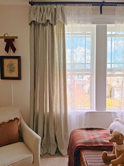 Classic linen striped curtains in neutral tones hanging by a window in a cozy living room setting