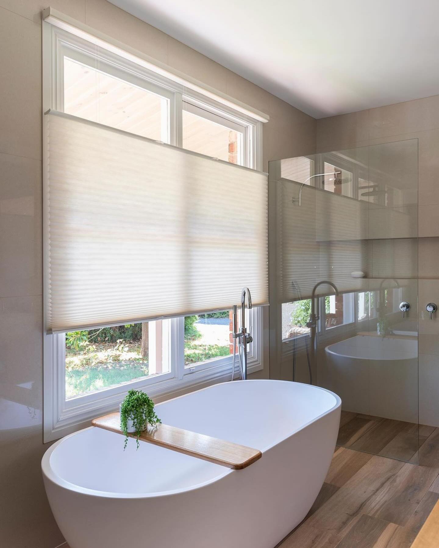 Elegant modern bathroom showcasing EaseEaseCurtains eco-friendly top-down bottom-up honeycomb shades in a serene setting with wooden flooring and oval bathtub