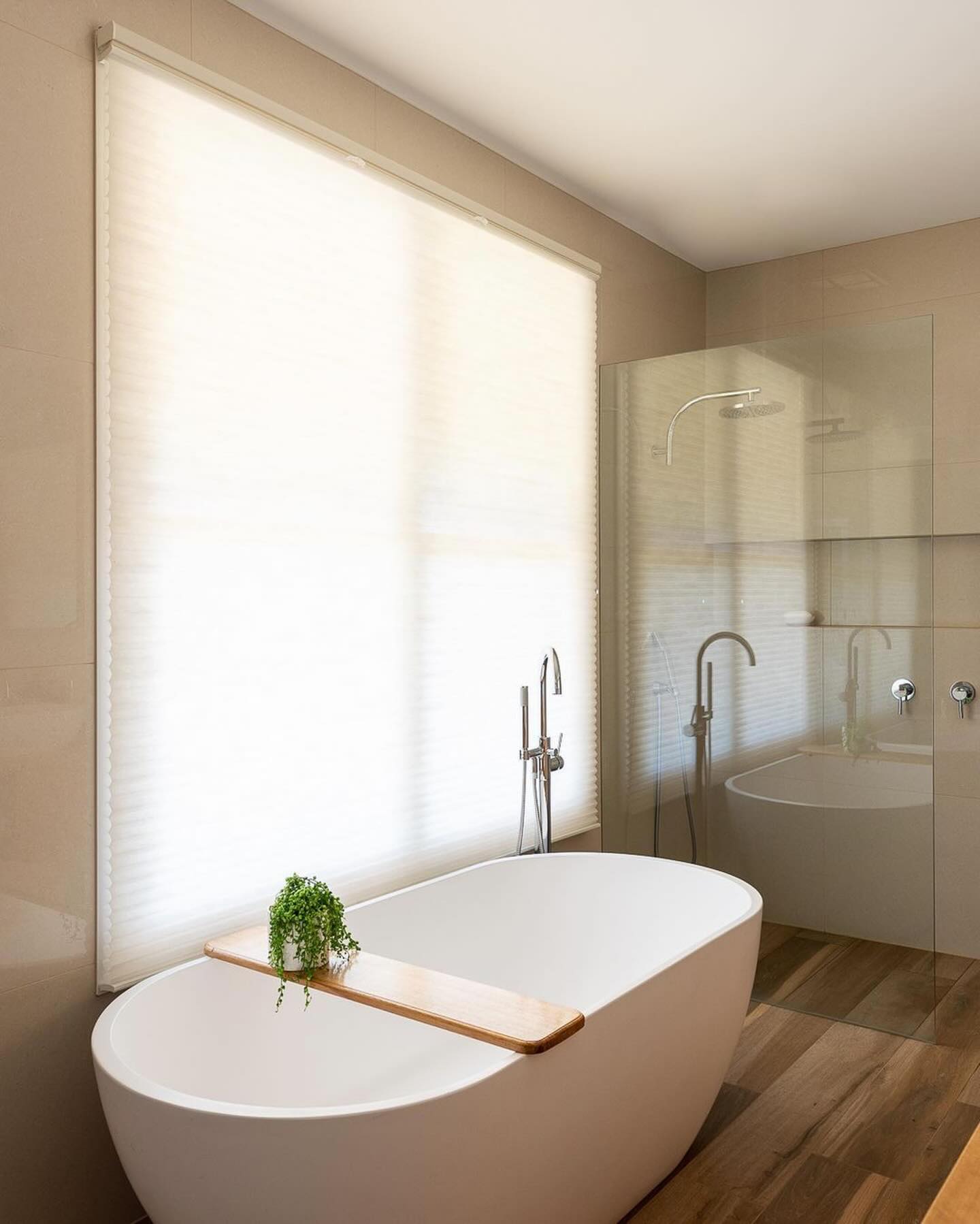 Elegant bathroom with cordless top-down honeycomb shade partially open over a freestanding bathtub, enhancing privacy and natural light