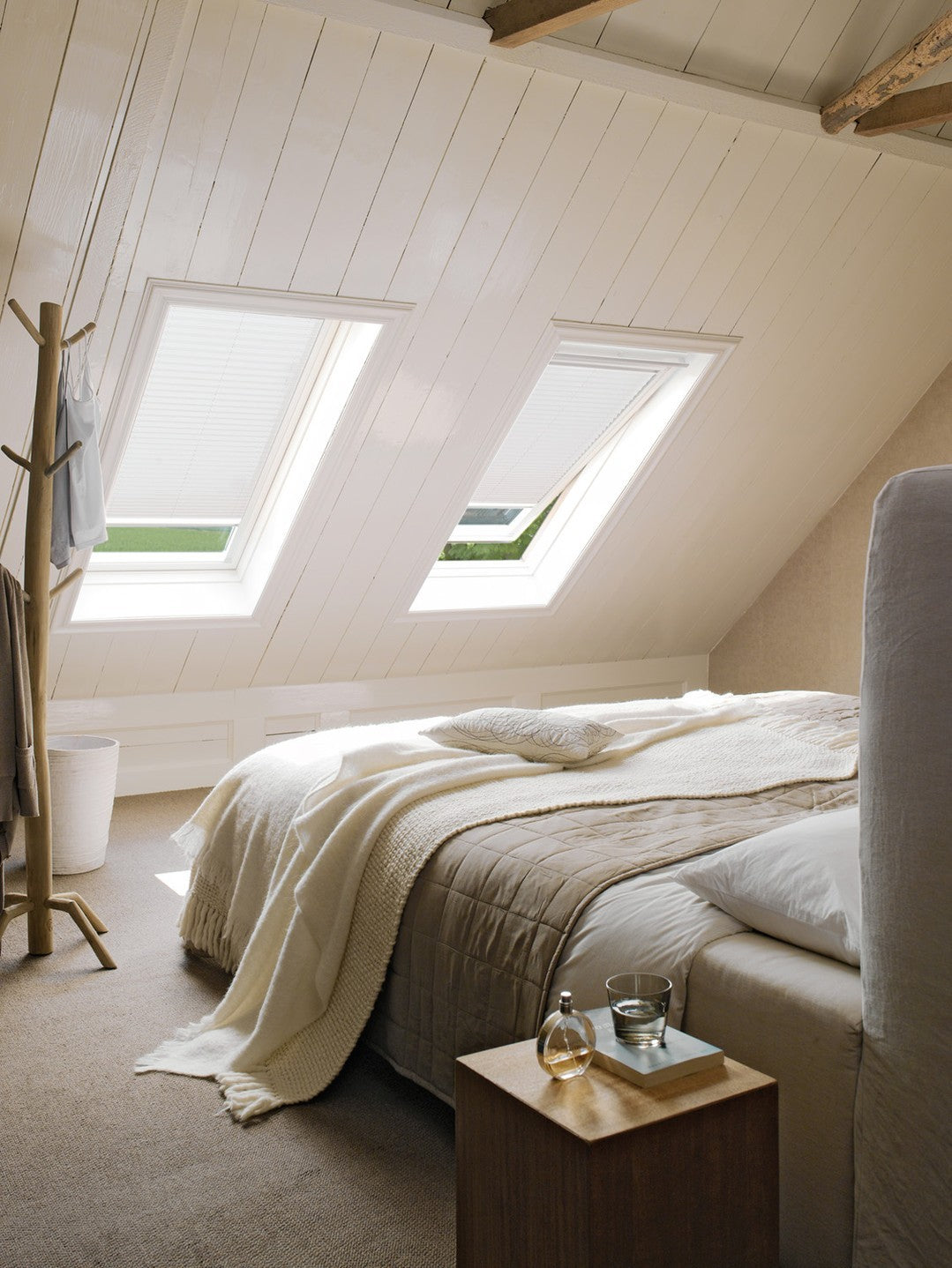 Cozy attic bedroom with sloped ceiling and skylights showcasing EaseEase Custom Sky Canopy Honeycomb Drapes in a serene home setting