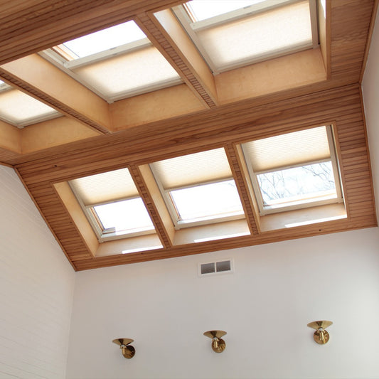 Vaulted ceiling with wood finish showcasing Sky Canopy Honeycomb Drapes on multiple skylights, enhancing natural light diffusion and room insulation
