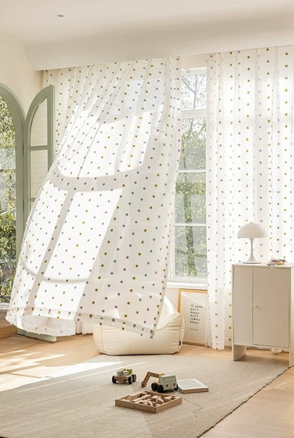 Colorful candy sheer curtains with rainbow pom-poms in a sunny kids' room, enhancing a playful and warm environment