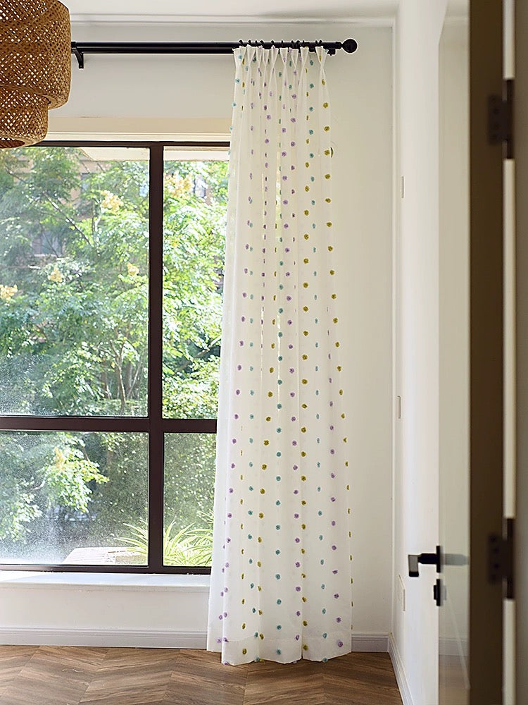 Colorful candy sheer curtain with rainbow pom-poms in a contemporary kids' room window, enhancing playful decor and natural lighting