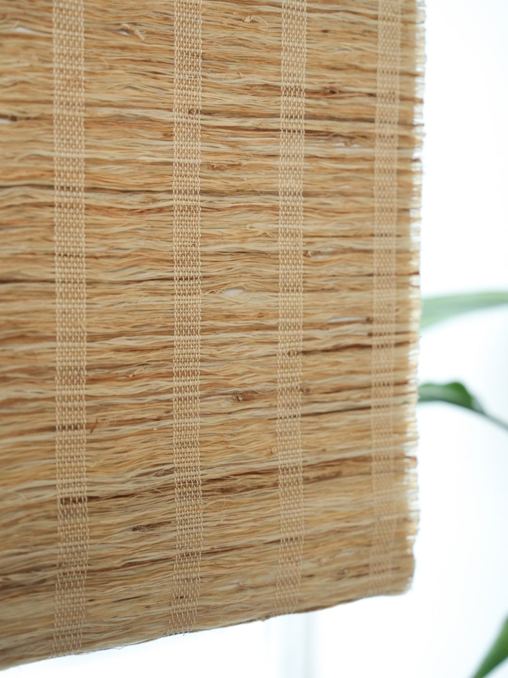 close-up of natural honey-colored woven shades made from 100% ramie fiber, showing breathable texture and warm organic tones