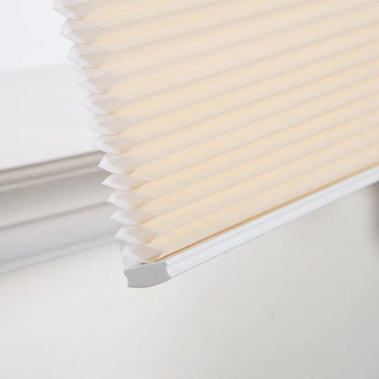 close-up of beige no-drill honeycomb shades with cordless, easy-install design on window frame